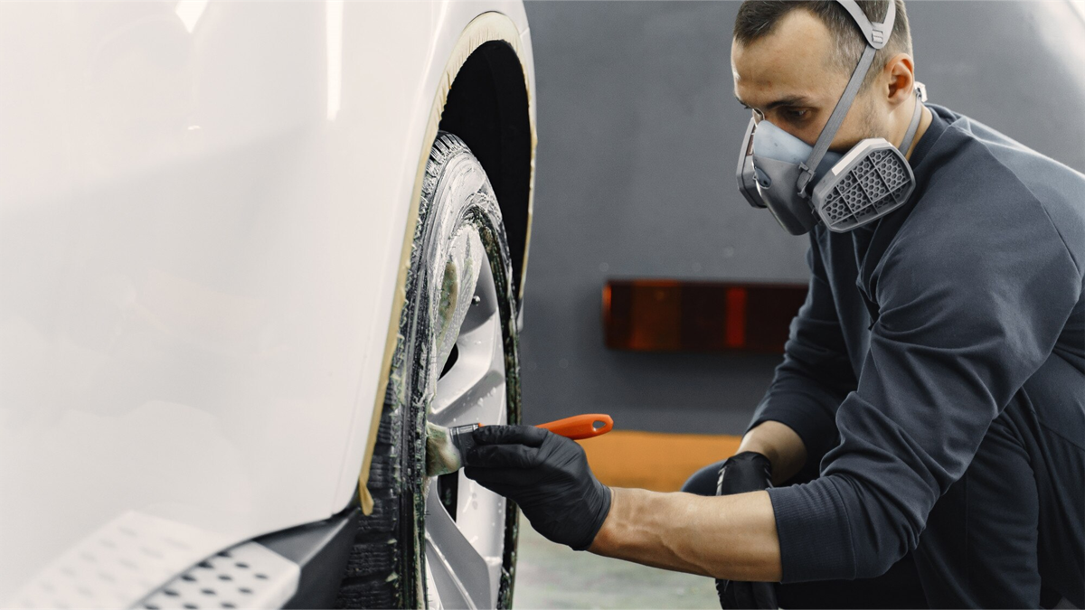 mężczyzna czyści alufelgi w aucie